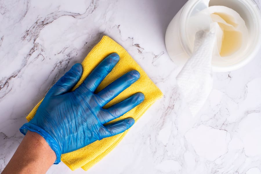 Main gantée essuyant un plan de travail en marbre avec une microfibre